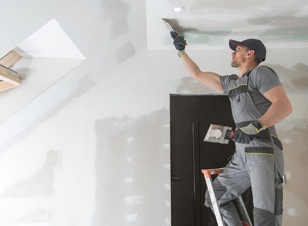 construction working patching dry wall on ceiling