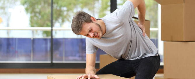 man with back injury from carrying heavy boxes